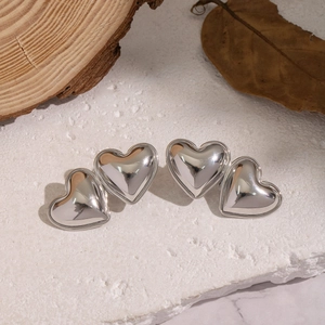 Detailed macro view of polished silver heart earrings in two sizes on a natural stone base