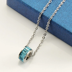 Macro view of a silver necklace featuring turquoise rectangular crystals on a blue gift box