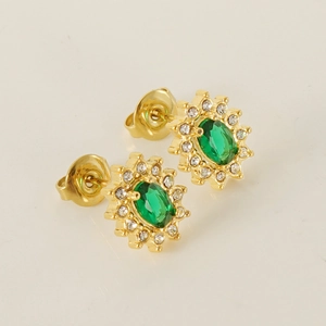 Gold sunflower earrings with emerald zircon center on a neutral minimalist background