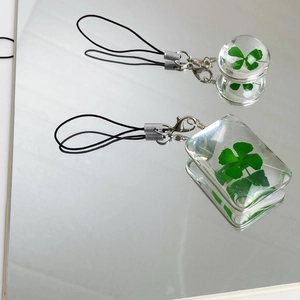 Detail of spherical and rectangular resin charms featuring real four-leaf clover specimens