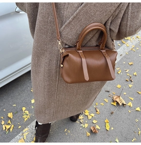 Detail einer gefalteten dunkelbraunen Boston-Tasche in herbstlicher Straßenszene mit Modell