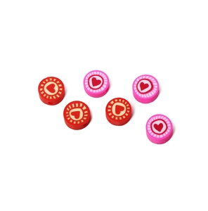 Flat lay of red and pink heart patterned polymer clay disc beads for DIY jewelry making