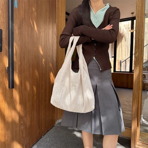 Detail of cream-white pleated tote bag with minimalist fabric texture and soft lighting