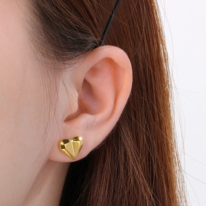Macro detail of gold 18k plated heart stud earrings with geometric faceted cut texture