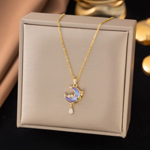 Macro detail of gold moon necklace with purple enamel and zircon inlay on jewelry box