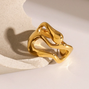 Macro detail of polished gold wavy stainless steel ring on textured stone surface