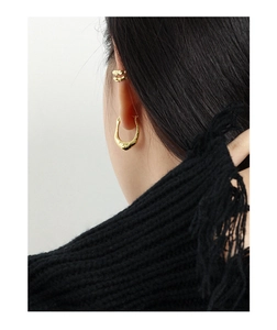Detailed close-up of golden textured irregular U-shape earring and ear cuff on model