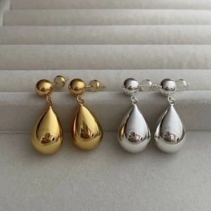 Classic gold and silver teardrop earrings with a polished mirror finish on velvet