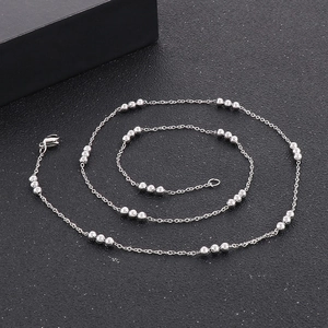 Detailed view of elegant silver beaded chain necklace on a textured black surface