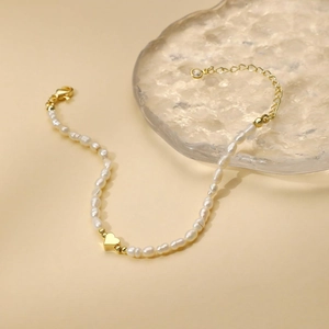 Dettaglio del bracciale con perle barocche, ciondolo a cuore dorato e chiusura a moschettone