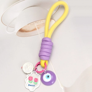 Détail d'un porte-clés tressé avec perle jaune, breloques fleurs et pendentif œil bleu
