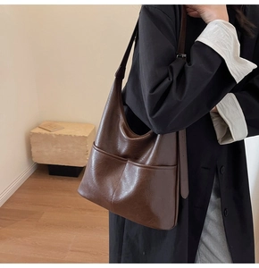 Deep brown soft leather tote bag with stitching detail shown in a minimalist room