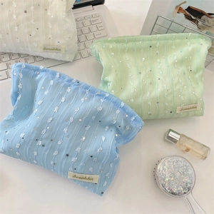 Gros plan de trois trousses à maquillage en dentelle et paillettes blanc, menthe et bleu