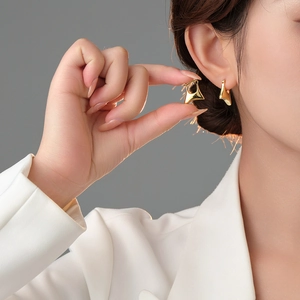 Detailed view of polished gold geometric earring on ear with minimalist modern design