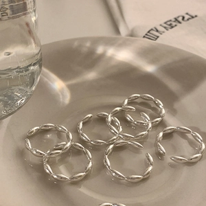 Diseño artístico de varios anillos de cadena plateados sobre un plato cerámico con luz suave