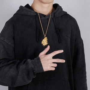 Golden Indian chief pendant on twist chain worn by model in gray hoodie detail view