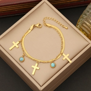 Double-layered golden cross necklace with turquoise gemstones in a jewelry box