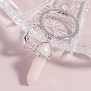Detail view of pink hexagonal crystal prism and silver moon charm on a metal keyring
