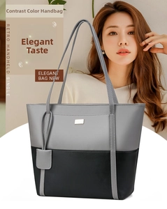 Detail of gray and black contrast stitching on a large leather tote bag with metal tag