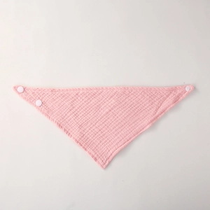 Detailed close-up of pink cotton gauze baby bib with breathable mesh and snap buttons
