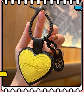 Detail of yellow and black leather heart keychain with embossed text and metal ring