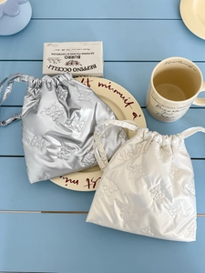 Detail of silver and cream drawstring bags with 3D butterfly embossing on tabletop