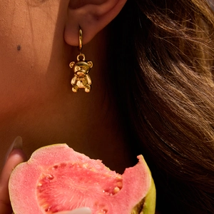 Detailed close-up of a 3D teddy bear drop earring in gold finish on a model's ear