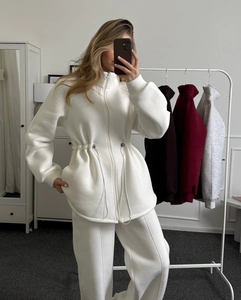 Detail of white zip-up hoodie with adjustable drawstring and ribbed cuff texture
