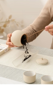 Detail view of a beige ceramic tea canister showing wide mouth design for easy access