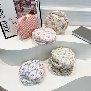 Various quilted cotton makeup bags with floral and heart patterns on white display stands
