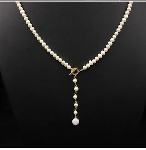 Macro shot of white pearls necklace with golden OT clasp and diamond accents