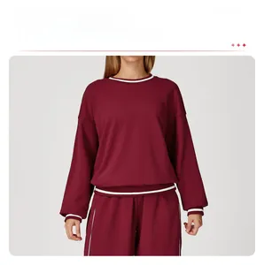Detail showing white ribbed contrast stitching on the neckline of a burgundy sweatshirt