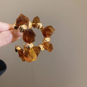 Makroaufnahme von modischen Bernstein-Resinperlen und Goldperlen an Creolen