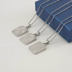 Polished stainless steel necklaces with rectangular letter pendants A and K on white surface