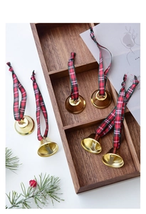 Detail view of golden metal Christmas bells with festive red and green plaid fabric ribbons