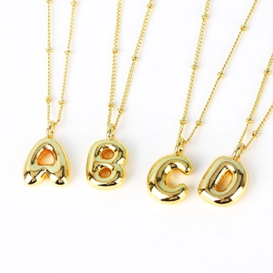 Detail of four gold-plated bubble letter pendants A B C D on beaded chains