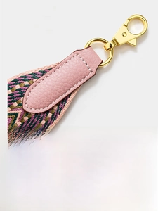 Macro detail of 5cm wide woven bag strap with pink leather end and gold buckle hardware