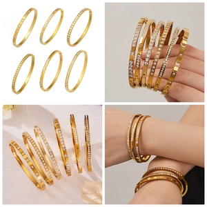 Dettaglio dei bracciali in acciaio placcati oro 18k con zirconi e incisioni a stella