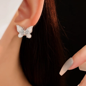 Close-up of elegant crystal butterfly pearl earrings on model with white enamel wings