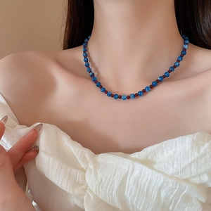 Close-up of a blue beaded necklace with red accents worn on a woman's neck