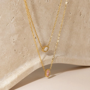 Collier classique en zircon ovale doré présenté sur un support en pierre naturelle