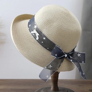 Summer straw sun hat with blue star ribbon and white bow on a wooden stand