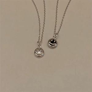 Detail showing two smiley face pendants in polished silver and vintage black finish