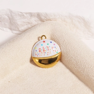 Detailed close-up of a gold-plated titanium pendant with colorful enamel art on beige fabric