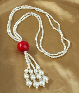 Detail of elegant multilayer pearl necklace with a bold red bead and cascading tassels