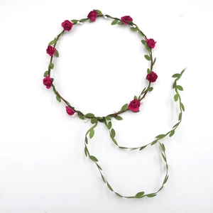 Detailed close-up of dark red rose floral headband with green leaves and vine ribbons