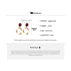 Detail view of burgundy resin studs with brushed gold oval rings and size measurements