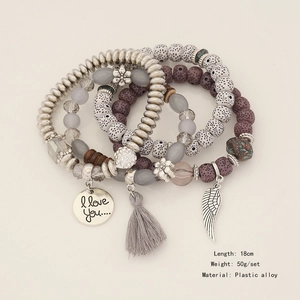 Detail of bohemian multilayer beaded bracelet with tassel, wing charm, and heart pendant