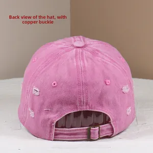Rear view of pink washed cotton baseball cap with adjustable copper buckle and distressed details