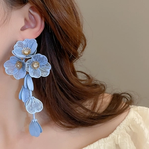 Detail of light blue floral tassel earrings with rhinestone centers and textured petals